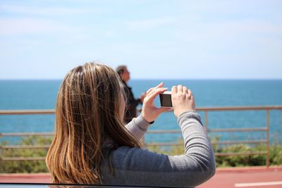 Rear view of woman photographing with digital camera