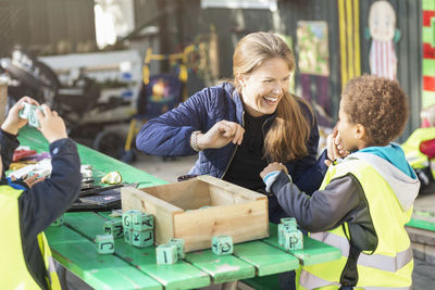 Happy teacher playing with blocks at table