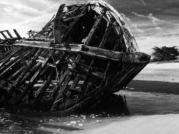 Abandoned boat in sea against sky