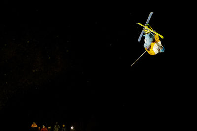 Man performing freestyle skiing jump at night