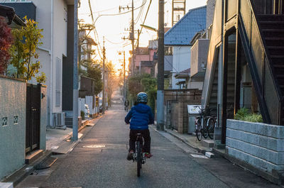 Rear view of man riding bicycle on street in city