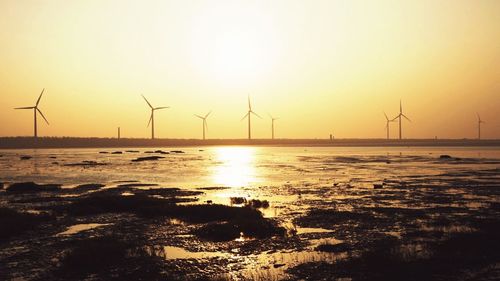 Wind turbines on landscape at sunset