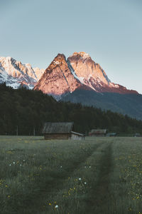 Scenic view of field by mountains against clear sky