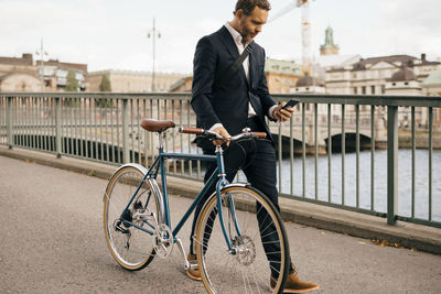 Man riding bicycle on bridge in city