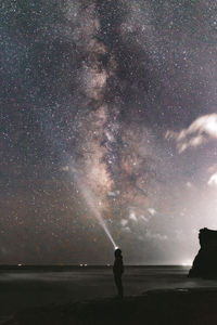 Man standing on beach against sky at night