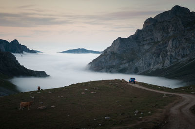 4x4 car in the mountains, driving on dirt road after sunset, heading into the fog.