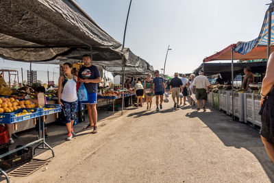 People at market stall against clear sky
