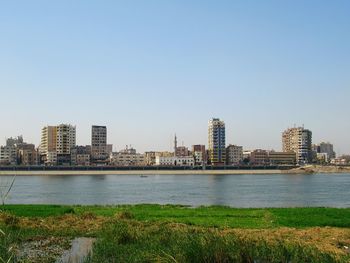 River by city buildings against clear sky