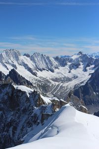 Scenic view of snowcapped mountains against blue sky