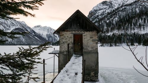 Snow covered house and trees against sky