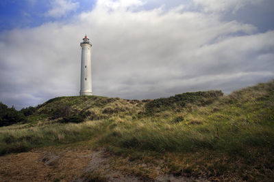 Lighthouse on field against sky