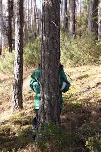 Boy playing with tree trunk in forest