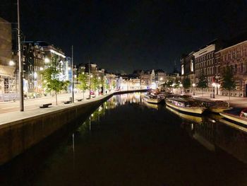 Canal amidst illuminated city buildings at night