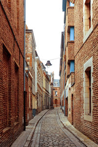 Alley amidst street in city against sky