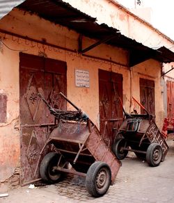 Old rusty wheelbarrows on street by houses