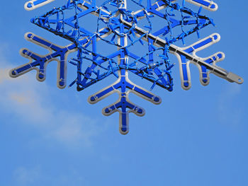 Low angle view of blue snow flake low section against blue sky