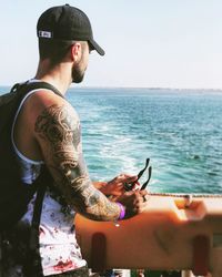 Side view of man standing on boat in sea against clear sky