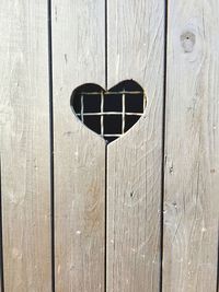 Close-up of wooden door with heart shape peephole