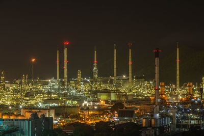 Illuminated factory against sky at night