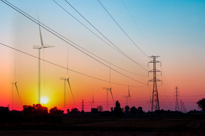 Silhouette electricity pylons on field against sky during sunset