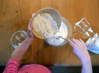 Directly above shot of girl mixing flour in bowl on table