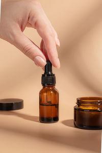 Close-up of hand holding bottle against white background