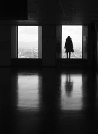 Rear view of silhouette woman standing on building window