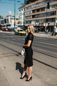 Fashionable woman standing against buildings in city