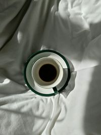 Directly above view of black coffee in cup on bed