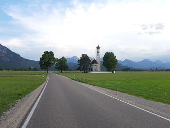 Road amidst green landscape against sky