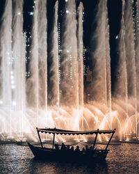 Fountain in sea against sky at night