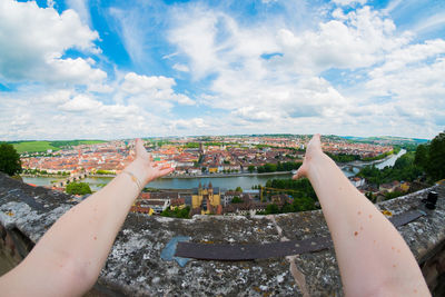 Cropped image of hand against cityscape against sky