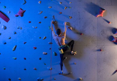 Unrecognizable boulderer with belay exercising on wall