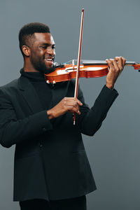 Midsection of man playing violin against white background