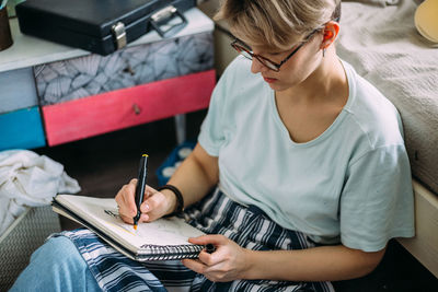 Midsection of woman using mobile phone while sitting on book