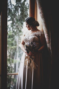 Rear view of woman standing by window