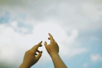 Low angle view of person hand against sky