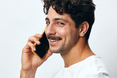 Close-up of young man using mobile phone against white background