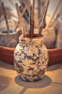 Glass, clay smeared smeared with brushes. a glass stained with smeared clay with tassels on table. 