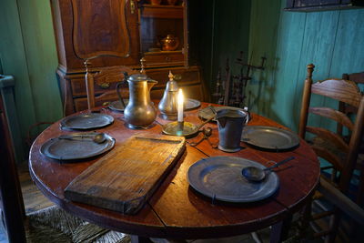 Illuminated candle with old kitchen utensils on table