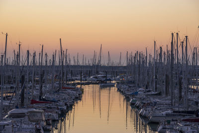 Boats moored at harbor against sky during sunset