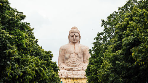 Low angle view of statue against trees against sky