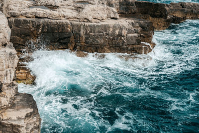 Scenic photo of waves against rocky sea shore.