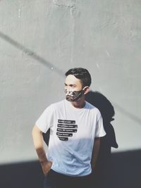 Portrait of young man standing against wall