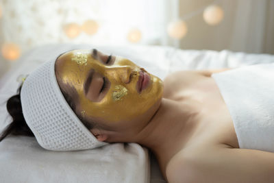 Young woman with facial mask lying on massage table