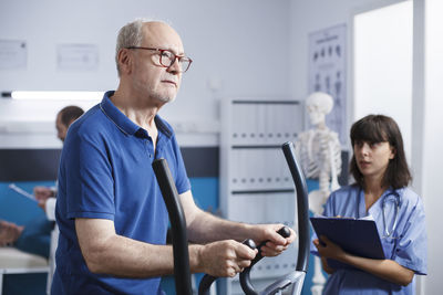 Side view of man using digital tablet while standing in office