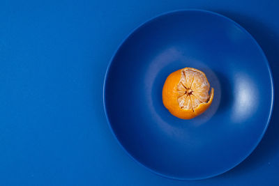 Half peeled tangerine on dark blue plate