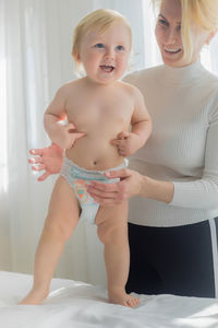 Mom holds the baby on the massage table. happy mom and baby laugh