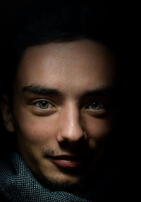 Close-up portrait of young man in dark room