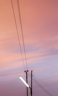 Low angle view of silhouette electricity pylon against sky during sunset